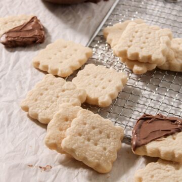 Looking down on some gluten-free shortbread cookies sitting on a cooling rack, some have been dipped into some chocolate.