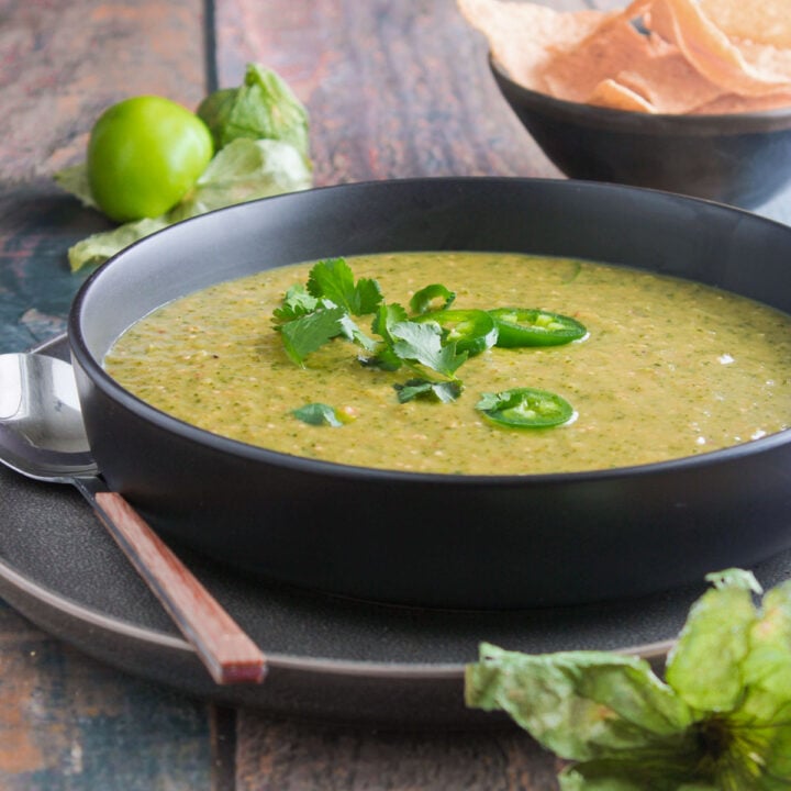 Salsa verde served in a black bowl garnished with cilantro and sliced jalapenos.